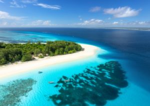 Luftaufnahme des blauen Meeres und der herrlichen Insel Mnemba, Sansibar Ferien. Blick von oben auf den weißen Sandstrand, grüne Bäume, Palmen, Meer mit klarem azurblauem Wasser an sonnigen Sommertagen. Tropische Landschaft. 